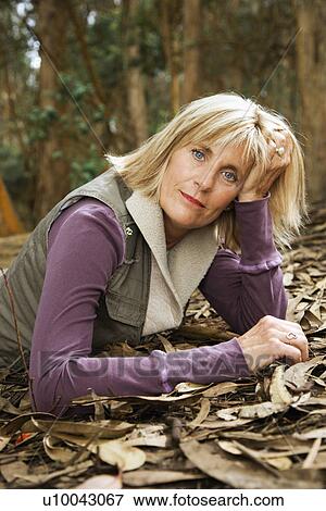 Middle-aged Caucasian woman lying on ground in forest. View Large Photo Image Stock Photo - Middle-aged Caucasian woman lying on ground in forest.. Fotosearch