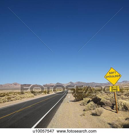 Road in desert with sign for soft shoulder and mountains in distance. View Large Photo Image Stock Photo - Road in desert with sign for soft shoulder and mountains in distance.. Fotosearch