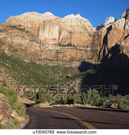 Two lane road winding through rocky desert cliffs in Zion National Park, Utah. View Large Photo Image Stock Photo - Two lane road winding through rocky desert cliffs in Zion National Park, Utah.. Fotosearch