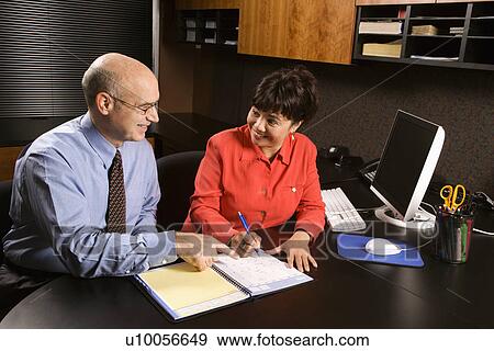 Stock Photo - Businessman and businesswoman in office going over appointment calendar.. Fotosearch