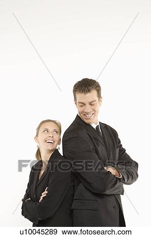Caucasian mid-adult businessman and woman standing back to back and smiling at each other. View Large Photo Image Stock Photo - Caucasian mid-adult businessman and woman standing back to back and smiling at each other. . Fotosearch