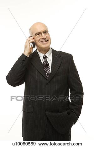 Stock Photo - Caucasian middle-aged businessman talking on cellphone against white background.. Fotosearch