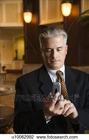 Caucasian prime adult male businessman dialing cellphone in hotel lobby. View Large Photo Image Stock Image - Caucasian prime adult male businessman dialing cellphone in hotel lobby.. Fotosearch
