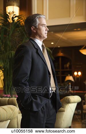 Stock Photo - Caucasian prime adult male businessman standing in hotel lobby.. Fotosearch