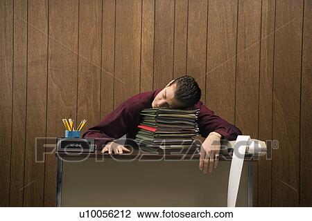 Caucasion mid-adult retro businessman sitting at desk resting his head on a tall stack of folders. View Large Photo Image Stock Image - Caucasion mid-adult retro businessman sitting at desk resting his head on a tall stack of folders.. Fotosearch