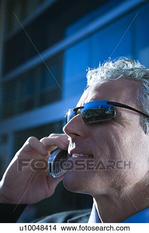 Close up side view of prime adult Caucasian man in suit talking on cellphone in urban setting. View Large Photo Image Picture - Close up side view of prime adult Caucasian man in suit talking on cellphone in urban setting.. Fotosearch