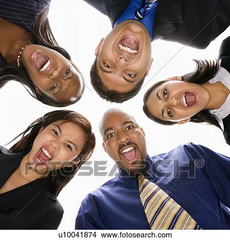 Low angle portrait of multi-ethnic business group of men and women in huddle screaming. View Large Photo Image Picture - Low angle portrait of multi-ethnic business group of men and women in huddle screaming.. Fotosearch