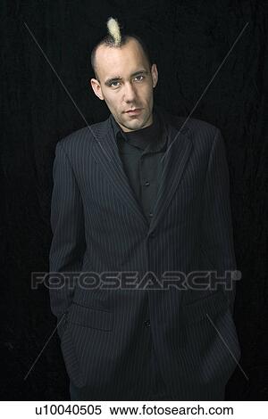Stock Photography - Portrait of Caucasian man in suit with mohawk against black background.. Fotosearch