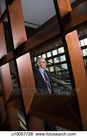 Stock Photo - Prime adult Caucasian man in suit riding on escalator.. Fotosearch