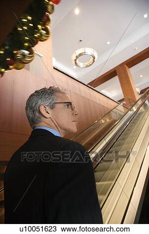 Rear view of prime adult Caucasian man in suit standing on escalator. View Large Photo Image Stock Image - Rear view of prime adult Caucasian man in suit standing on escalator.. Fotosearch