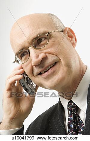 Smiling Caucasian middle-aged businessman talking on cellphone against white background. View Large Photo Image Stock Photo - Smiling Caucasian middle-aged businessman talking on cellphone against white background.. Fotosearch