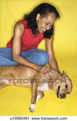 Stock Photo - African American prime adult female petting dog.. Fotosearch