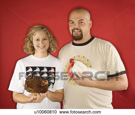 Stock Image - Caucasian mid-adult male and female holding chickens.. Fotosearch