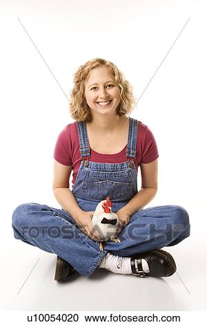 Stock Image - Caucasian mid-adult woman holding Old English Bantam Rooster wearing bow tie.. Fotosearch