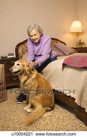 Stock Image - Elderly Caucasian woman and dog in bedroom at retirement community center.. Fotosearch