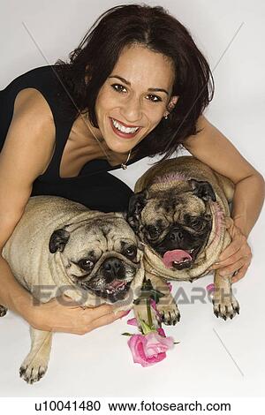 Stock Image - Caucasian female prime adult with two Pug dogs.. Fotosearch