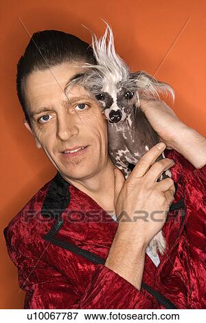 Stock Photo - Caucasian mid-adult male wearing velvet jacket and holding Chinese Crested dog.. Fotosearch