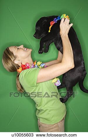 Stock Image - Caucasian prime adult female holding black puppy.. Fotosearch