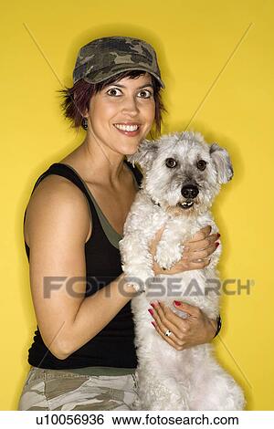 Stock Photograph - Hispanic mid-adult woman female holding small white dog.. Fotosearch