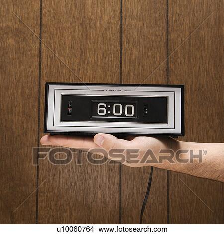 Caucasion male hand holding retro clock set for 6: 00 against wood paneling. View Large Photo Image Picture - Caucasion male hand holding retro clock set for 6: 00 against wood paneling.. Fotosearch