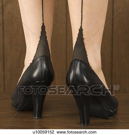 Stock Image - Close-up shot of Caucasian female legs and black heels.. Fotosearch