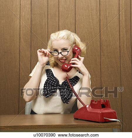 Stock Image - MId-adult Caucasian female dressed in retro outfit holding a red phone.. Fotosearch