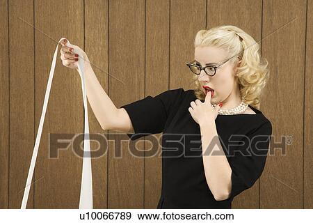 Stock Photo - Mid-adult Caucasian female in vintage outfit holding a printout with finger on her lip.. Fotosearch