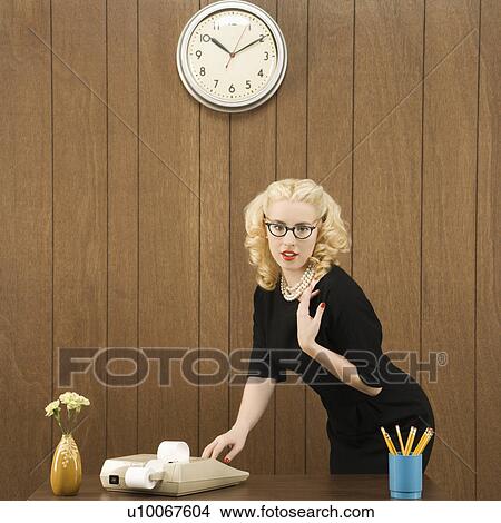 Mid-adult Caucasian female wearing vintage outfit in office touching calculator. View Large Photo Image Picture - Mid-adult Caucasian female wearing vintage outfit in office touching calculator.. Fotosearch
