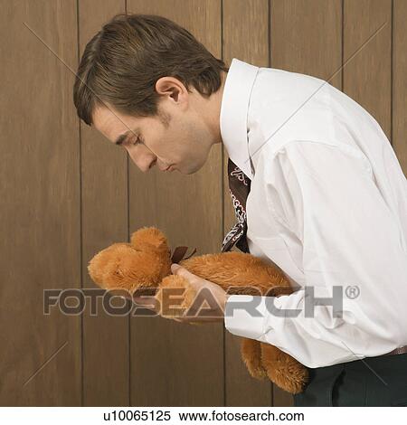 Stock Photography - Mid-adult Caucasian male holding a stuffed animal preparing to kiss it.. Fotosearch