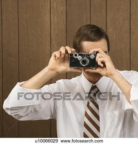 Mid-adult Caucasian male holding vintage camera up to his face. View Large Photo Image Stock Photo - Mid-adult Caucasian male holding vintage camera up to his face.. Fotosearch