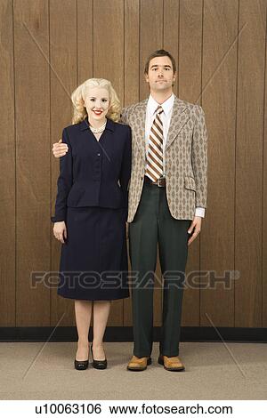 Stock Photograph - Mid-adult Caucasian male in retro suit with arm around mid-adult Caucasian female.. Fotosearch