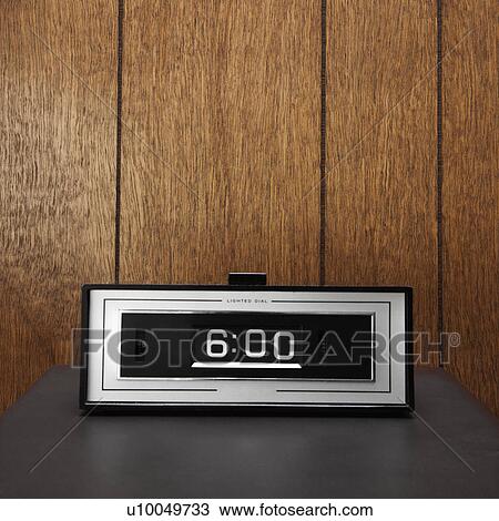 Stock Image - Retro clock set for 6: 00 against wood paneling.. Fotosearch