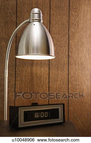 Retro scene of desk lamp shining on retro clock set for 6: 00 against wood paneling. View Large Photo Image Stock Photograph - Retro scene of desk lamp shining on retro clock set for 6: 00 against wood paneling.. Fotosearch