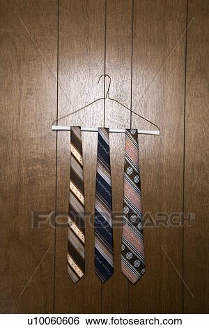 Three retro ties hanging on a wire hanger against wood paneling. View Large Photo Image Stock Photograph - Three retro ties hanging on a wire hanger against wood paneling.. Fotosearch
