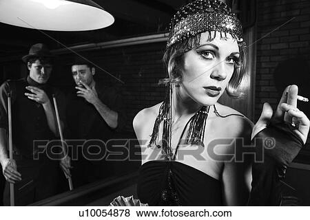 Stock Photo - Caucasian prime adult female standing in front of pool table with two Caucasian prime adult men in background.. Fotosearch
