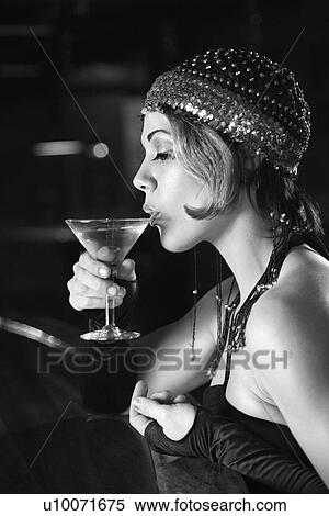 Stock Photography - Caucasian prime adult retro female sitting at bar drinking martini.. Fotosearch