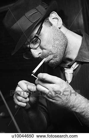 Stock Image - Caucasian prime adult retro male lighting cigarette.. Fotosearch