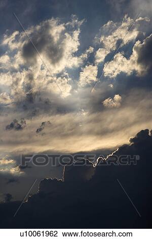 Stock Image - Sun peeking through clouds.. Fotosearch