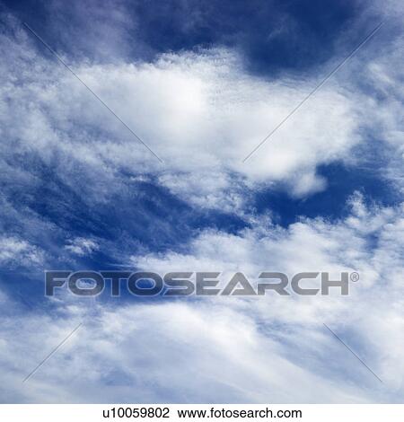Stock Image - Wispy cloud formations against clear blue sky.. Fotosearch