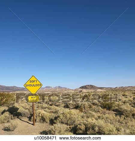 Stock Image - Road sign in desert for soft shoulder and mountains in distance.. Fotosearch