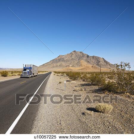 Stock Photography - Tractor trailer driving on desert road with mountain in background.. Fotosearch