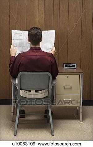 Stock Photo - Back view of retro businessman sitting at desk reading paper.. Fotosearch
