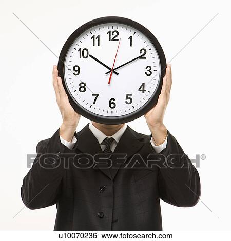 Caucasian man wearing suit holding clock in front of face. View Large Photo Image Stock Photograph - Caucasian man wearing suit holding clock in front of face.. Fotosearch
