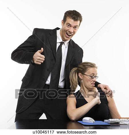 Caucasian mid-adult man sexually harassing woman sitting at computer and giving thumbs up. View Large Photo Image Stock Photo - Caucasian mid-adult man sexually harassing woman sitting at computer and giving thumbs up.. Fotosearch