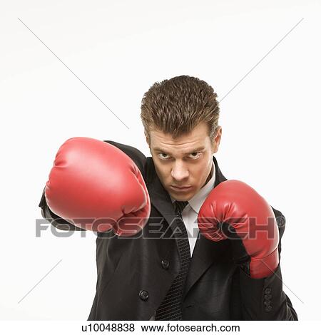 Stock Photo - Caucasian mid-adult man wearing suit and punching with boxing gloves toward viewer.. Fotosearch