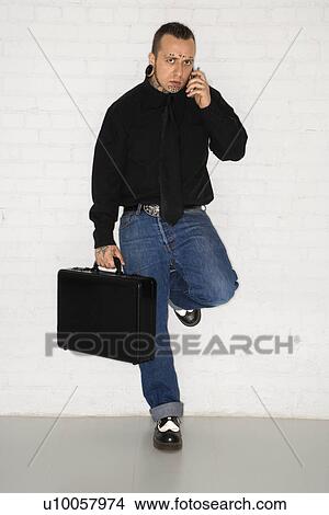 Caucasian mid-adult man with tattoos and piercings talking on cell phone. View Large Photo Image Picture - Caucasian mid-adult man with tattoos and piercings talking on cell phone.. Fotosearch