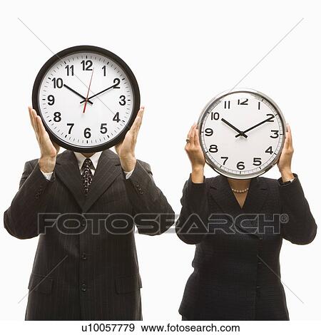Stock Photo - Caucasian middle-aged businessman and Filipino businesswoman holding clocks in front of their heads standing against white background.. Fotosearch