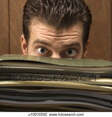 Caucasion mid-adult retro businessman peering with wide eyes over a tall stack of folders. View Large Photo Image Stock Image - Caucasion mid-adult retro businessman peering with wide eyes over a tall stack of folders.. Fotosearch
