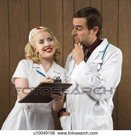 Stock Photograph - Mid-adult Caucasian female nurse smiling at male doctor making facial expression.. Fotosearch
