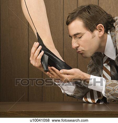 Stock Photo - Mid-adult Caucasian male holding Caucasian female shoe and preparing to kiss it.. Fotosearch